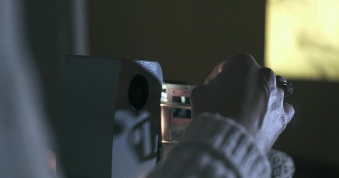 Photographer Projects Photo Slides On To Wall With Projector.
