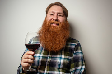 A red-bearded man drinking wine from a large glass. A vine tasting at home. Sommelier for yourself at home. A man with a big beautiful beard.