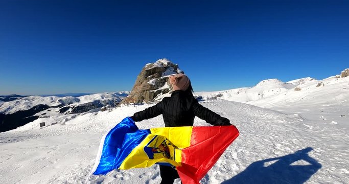 Girl running with the Romanian Flag on top of The Bucegi Mountains, towards the Sphinx rock in Romania - slow motion shot