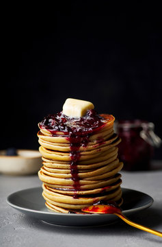 A stack of pancakes with jam and butter