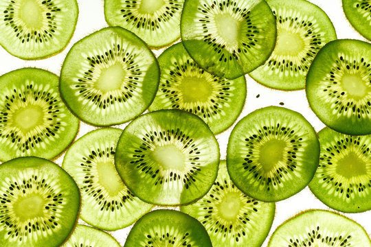 Backlit kiwi fruit slices on white background. Top view texture
