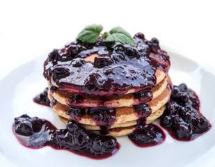 Leckere amerikanische Pancakes mit Beerensauce auf einem weißen Teller