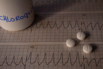 Adverse effects on the heart by hydroxychloroquine or chloroquine. Pills on an electrocardiogram...