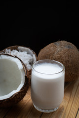 Coconut and a glass of coconut milk on a wooden background. Healthy food.