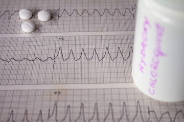 Adverse effects on the heart by hydroxychloroquine or chloroquine. Pills on an electrocardiogram...