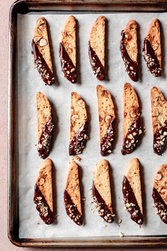 Rows of chocolate dipped hazelnut biscotti on a baking tray.