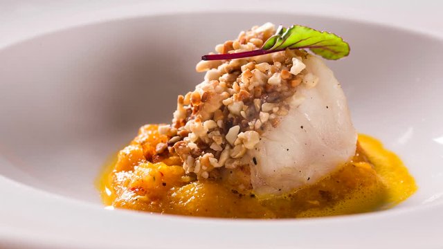 Roasted cod, codfish with baked pumpkin. Front view with smoke