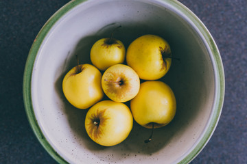 plant-based ingredients, group of golden delicious apples in bowl on kitchen countertop