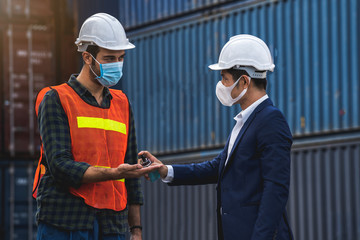 The supervisor wearing a protective surgical mask, standing for a physical examination and pressing the alcohol gel to colleague before into workplace at the warehouse container