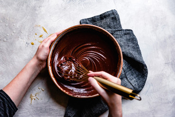 Woman's hands mixing chocolate ganache in bowl