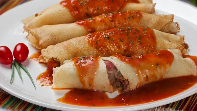 Delicious sliced pancakes with meat and tomato sauce. Smoke.