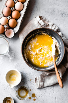 Pancake mixture in a bowl with a wooden spoon.