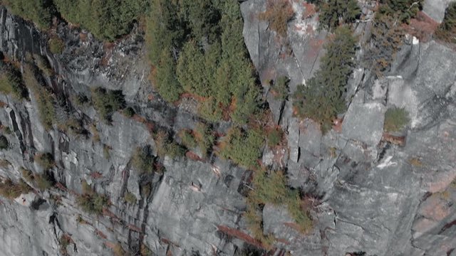 Rocky Cliffs Of Mount Pinacle With Lush Green Trees In Quebec, Canada At Daytime With Serene Lake. - aerial drone