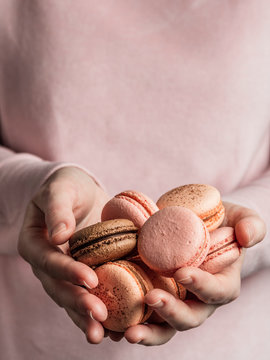 Macarons heap in female hands, vertical