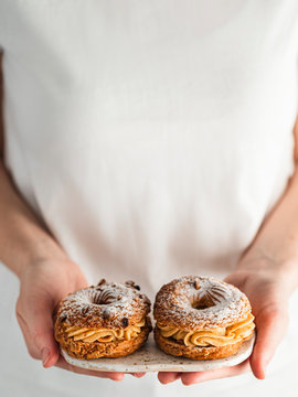 Woman holds two Choux Paris Brest pastry