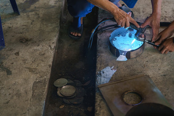 Asian worker using plasma cutter for cutting modified bottomless portafilter