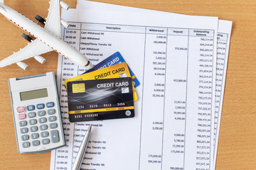Airplane model and calculator on Bank statement and credit card on a Wooden table. Finance about...