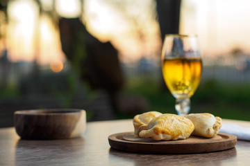 Argentine empanadas on a wood plate and beer outside