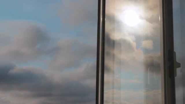Timelapse of clouds on blue sky and as reflection on glass