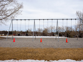 Fototapeta na wymiar Closed school playground swings with orange pylon cones due to the covid 19 pandemic