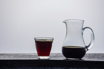 A jug and a glass of black coffee on a wooden table Background fog.