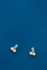 Representation of male genitalia with pills. Penis formed with pills on blue background.