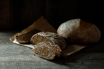Healthy rye whole grain round bread on brown craft paper on black wooden table. Home baked