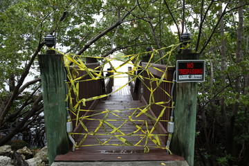 Fototapeta premium yacht pier or bridge is closed to visitors with yellow tape. The plate with the inscription but the trespassing. Covid-2019