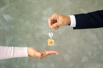 The salesman in the suit was sending the house keys to the new landlord. The buyer receives the key from the seller. Concept of buying and selling house