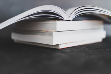 stack of books with one open on top of themshot from eye level with shallow depth of field