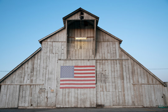 Old barn at dusk with American flag. - Powered by Adobe