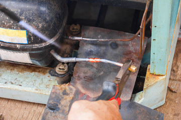 repair old refrigerator job,technician welding copper pipe by gas before vacuum system at...