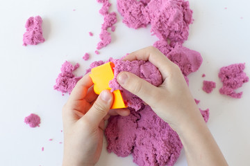 Purple kinetic sand in hand isolated on a white background. Colored sand for modeling for children.