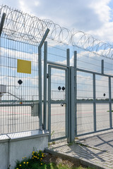 Entrance to the fence from the grill and barbed wire. Space for text on a plate.