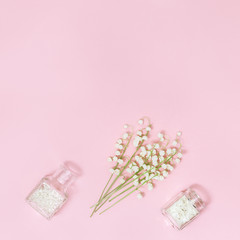 Small first spring flowers lilies of the valley and beautiful glass bottle with dried petals for aromatherapy. Spring or spa background with space for text. Creative flat lay with copy space.