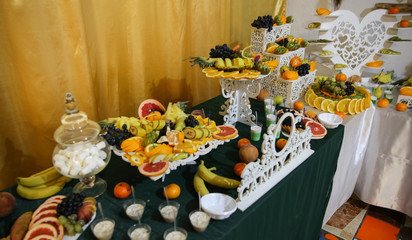 Stylish luxury decorated tables for the celebration of a wedding day of happy couple, cathering in the restaurant. Decoration with fruit for child birthday.