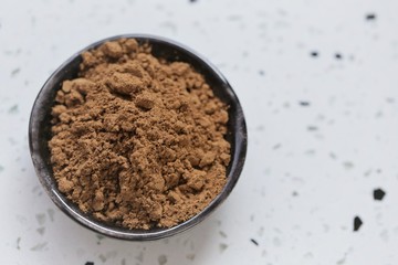 guarana powder in a black cup on a white marble board.View from above.Super food.Portion of Guarana Powder. Useful product. Healthy eating concept. Natural energetic. copy space.