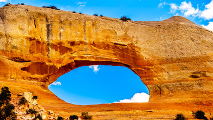 Wilson Arch under blue sky, a sandstone arch along US Highway 191, south of the town of Moab in Utah, United States