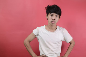 Young man who is expressionally annoyed. Asian men wearing white t shirts isolated on a red background