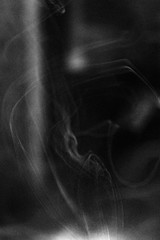 Black-and-white film frame with a massive grain on which there are clouds of cigarette smoke floating in the air.