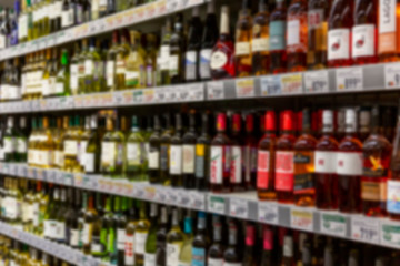 Wine bottles on shelves in a store. Large assortment of alcohol. Blurred.