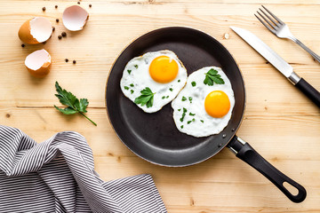 Fried eggs on frying pan on beige desk top-down
