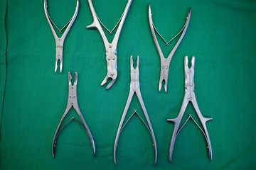 different surgical bone forceps lie side by side on a surgical drape