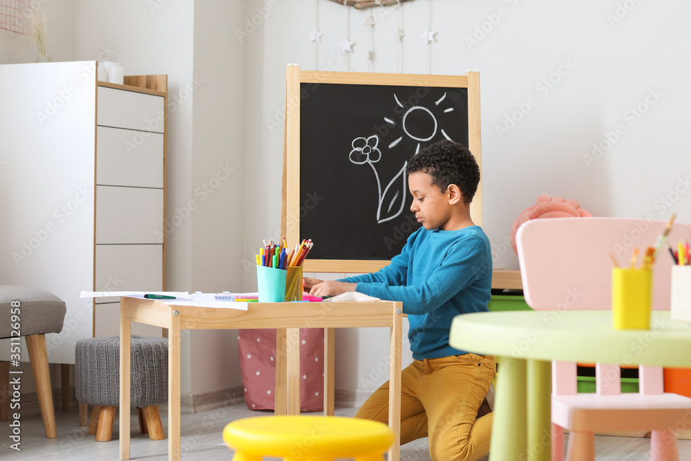 Sticker Cute African-American boy drawing at school