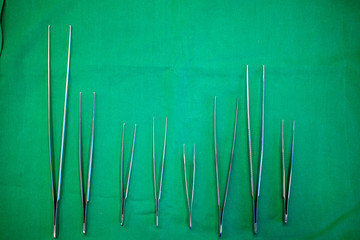 different surgical forceps lie side by side on a surgical drape
