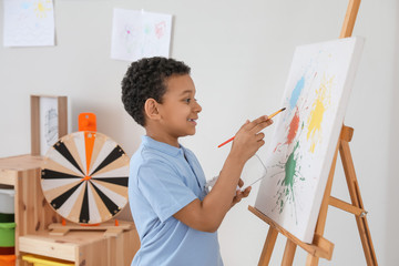 Cute African-American boy painting at school