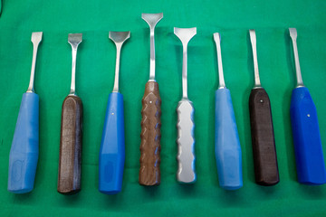 some different surgical chisels lie side by side on a surgical drape