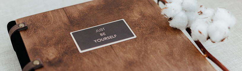Luxury wooden photo book with just be yourself sign on linen natural background.