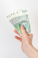Five 100 PLN banknotes held in right hand.