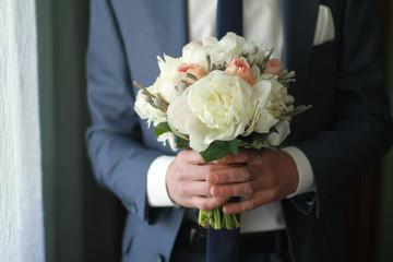 Wedding bouquet of flowers in the hands of the groom in a suit.
